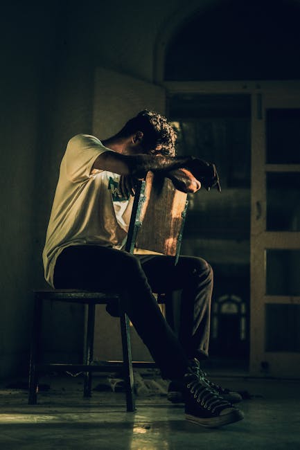 Man in a seated meditation pose inside a modern, light-filled room.