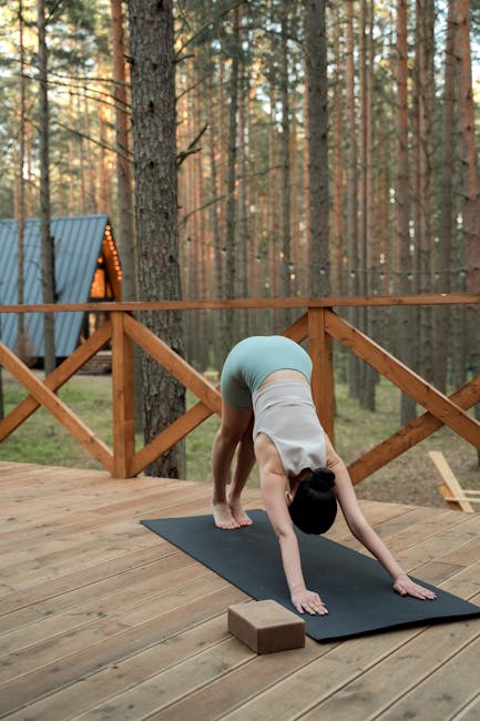 Woman practicing a peaceful yoga pose outdoors on a wooden deck by the water.